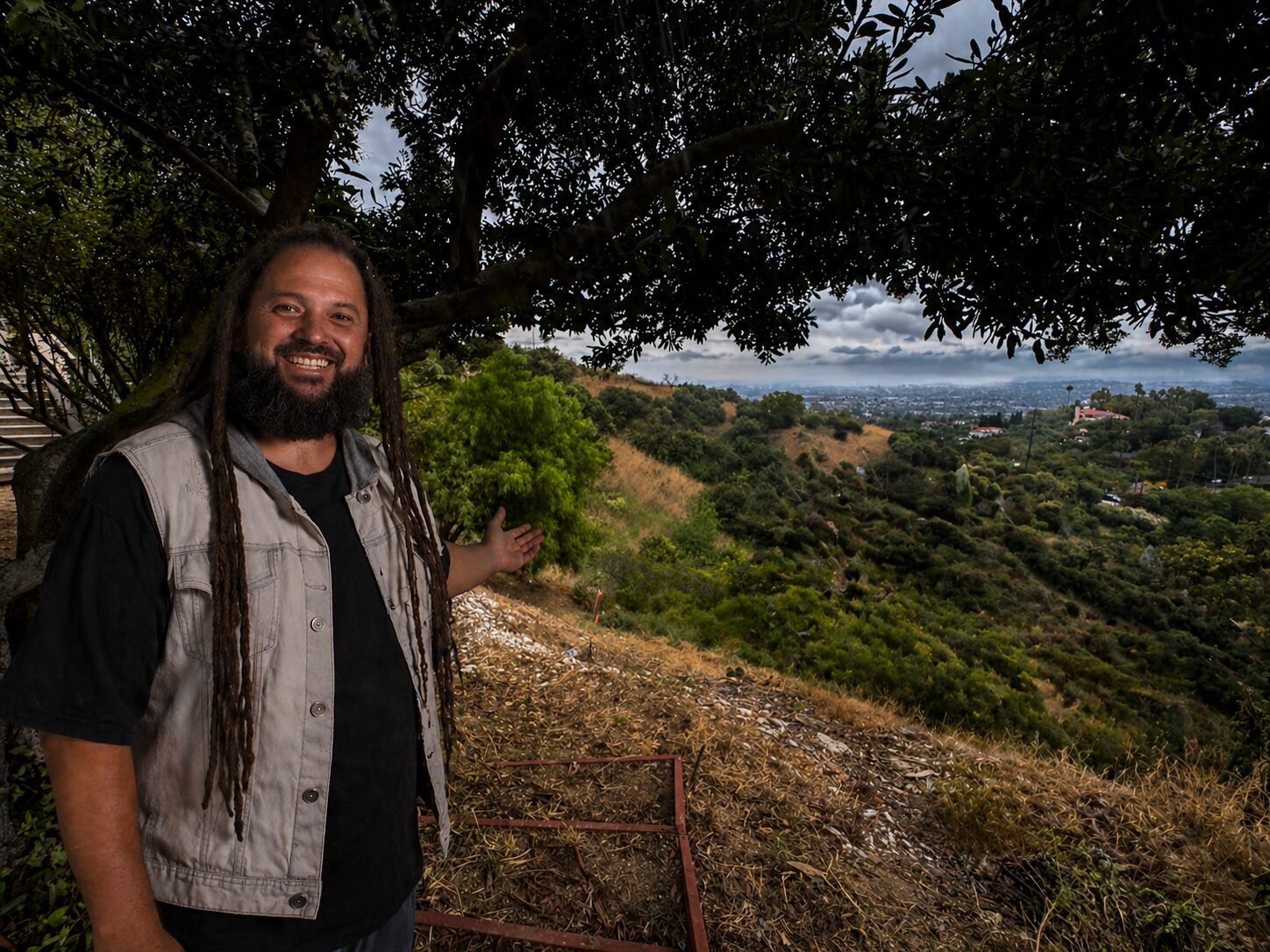 Keith Bennett walking the back of a five-acre hillside — unused brush-cleared land overlooking the basin, on the cloudy morning of the property visit.