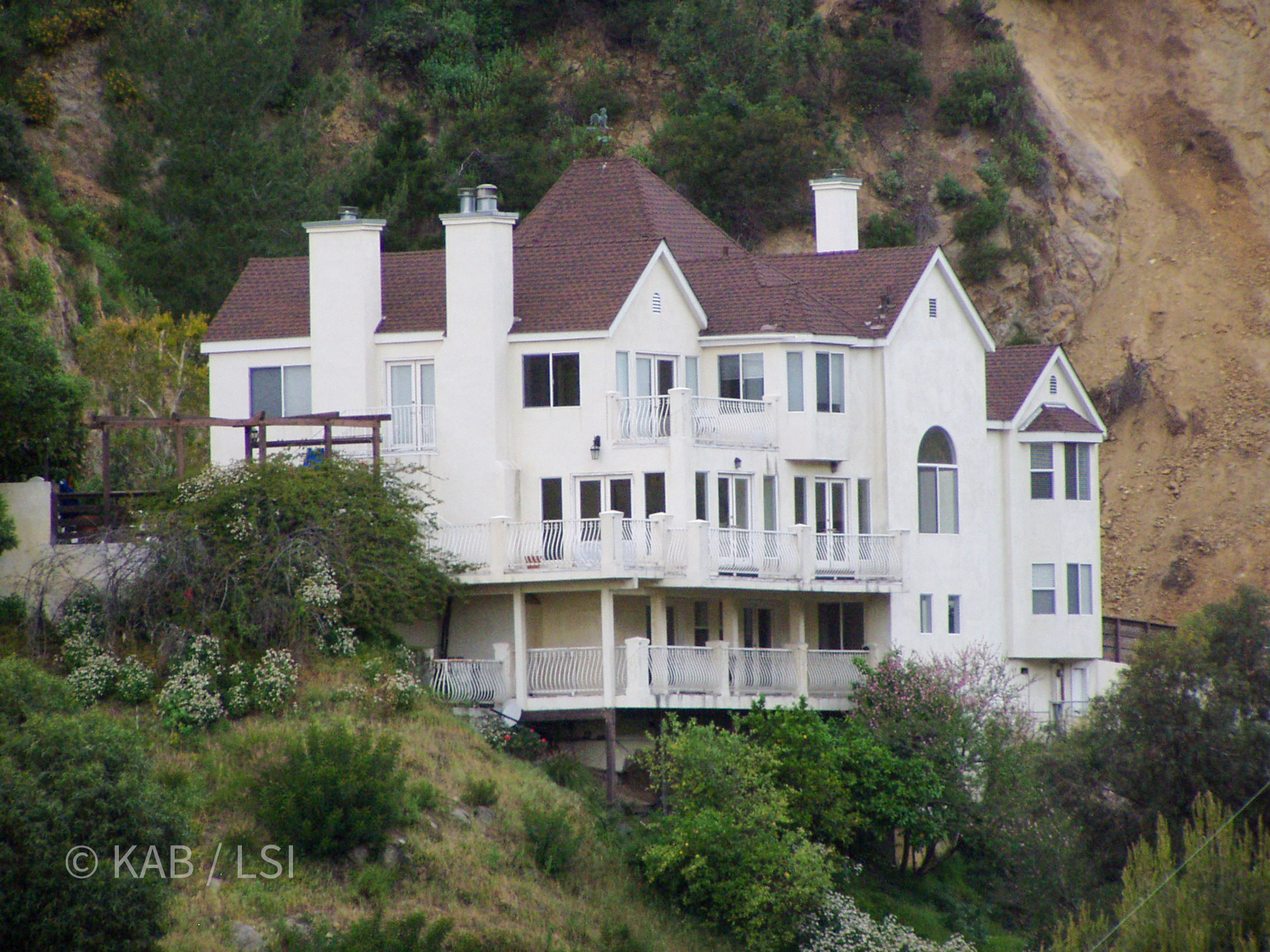 The house above Laurel Canyon that wouldn’t stop moving — a white Victorian on a crumbling hillside, red-tagged after the slope failed. © KAB/LSI
